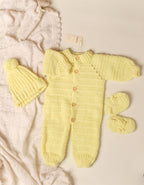 Yellow knitted baby outfit with hat and booties on a beige background